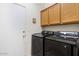 Laundry room with modern washer and dryer units and overhead storage cabinets at 9608 E Nacoma Dr, Sun Lakes, AZ 85248