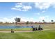 Golf course with a pond, cart path, and golf carts, with houses visible in the background at 9608 E Nacoma Dr, Sun Lakes, AZ 85248