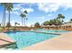 Resort-style pool with palm trees, lounge chairs, and clear blue water on a sunny day at 9608 E Nacoma Dr, Sun Lakes, AZ 85248