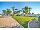 Green backyard featuring an artificial lawn surrounded by mature trees and paver stones at 10059 W Villa Lindo Dr, Peoria, AZ 85383