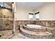 The bathroom has a large soaking tub surrounded by brown tile and a glass enclosed shower at 10059 W Villa Lindo Dr, Peoria, AZ 85383