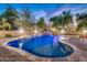 Beautiful backyard pool with a rock waterfall and slide feature, surrounded by lush landscaping at 10059 W Villa Lindo Dr, Peoria, AZ 85383