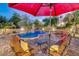 Outdoor seating area with a large red umbrella, overlooking a beautiful pool with a rock waterfall and slide at 10059 W Villa Lindo Dr, Peoria, AZ 85383