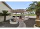 The outdoor kitchen in the backyard has a built-in barbecue with a manicured landscape and tall palm trees at 15948 W Sheila Ln, Goodyear, AZ 85395