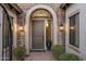 Close-up of a home's front door, featuring stone accents, potted plants, and outdoor lighting at 18491 N 98Th Way, Scottsdale, AZ 85255