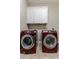 Functional laundry area with front-loading washer and dryer beneath storage cabinets at 18491 N 98Th Way, Scottsdale, AZ 85255