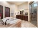 Luxurious bathroom featuring a soaking tub, a double sink vanity, and a glass door shower with a fireplace at 19717 E Country Meadows Dr, Queen Creek, AZ 85142