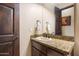Powder room showcasing granite counters, a wood cabinet, and a decorative mirror at 19717 E Country Meadows Dr, Queen Creek, AZ 85142