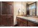 Powder bathroom with wood door, granite counters and mirror to give a warm feeling at 19717 E Country Meadows Dr, Queen Creek, AZ 85142