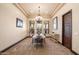Bright dining room with elegant chandelier, large windows, and simple furnishings at 19717 E Country Meadows Dr, Queen Creek, AZ 85142