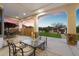 Covered outdoor patio with stone columns, seating and sunset view for dining and relaxation at 19717 E Country Meadows Dr, Queen Creek, AZ 85142