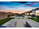 Backyard with a pool, lounge chairs, an outdoor kitchen, and lush landscaping at dusk at 22372 E Duncan St, Queen Creek, AZ 85142