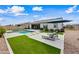 A modern backyard featuring a sparkling pool, artificial turf, and comfortable lounge seating with an umbrella at 22372 E Duncan St, Queen Creek, AZ 85142