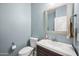 Charming powder room with light blue walls, toilet, sink, mirror, and towel rack at 2336 W Magdalena Ln, Phoenix, AZ 85041