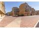 View of street lined with townhomes featuring attached garages and red brick paved street at 240 W Juniper Ave # 1053, Gilbert, AZ 85233