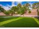 This backyard features artificial grass, mature trees, a retaining wall, and a small fountain at 25425 N 64Th Ave, Phoenix, AZ 85083
