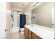 Bright bathroom with a single sink vanity, tiled floors, and a shower-tub combo with curtain at 25695 W Crown King Rd, Buckeye, AZ 85326