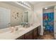 This bathroom features dual sinks, tile floors, and themed shower curtain at 5917 N 133Rd Ave, Litchfield Park, AZ 85340