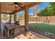 Spacious covered patio with dining area overlooking the backyard with a putting green, lush landscaping, and outdoor kitchen at 5917 N 133Rd Ave, Litchfield Park, AZ 85340