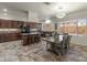 Bright kitchen with dark wood cabinets, granite counters, island, and dining area with modern chandelier at 5917 N 133Rd Ave, Litchfield Park, AZ 85340