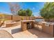 Well-equipped outdoor kitchen with stainless steel grill and adjacent firepit, perfect for outdoor entertaining and relaxation at 5917 N 133Rd Ave, Litchfield Park, AZ 85340