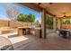 Well-appointed outdoor kitchen with built-in grill and bar area on covered patio with adjacent firepit and lush backyard at 5917 N 133Rd Ave, Litchfield Park, AZ 85340