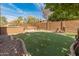 Lush putting green surrounded by mature trees and landscaping, with outdoor kitchen and firepit, perfect for outdoor activities at 5917 N 133Rd Ave, Litchfield Park, AZ 85340