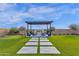 An alluring backyard fire pit area with stone pathway and modern pergola in a manicured lawn setting at 6790 S Springs Pl, Chandler, AZ 85249