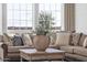 Close-up of a comfortable sectional with accent pillows, coffee table, and a large window in a sunlit living room at 6790 S Springs Pl, Chandler, AZ 85249