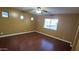 A spacious bedroom featuring hardwood floors, a ceiling fan, and bright natural light from multiple windows at 7511 S 45Th Dr, Laveen, AZ 85339