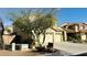 View of a two-story home with a three-car garage, partially obscured by a tree at 7511 S 45Th Dr, Laveen, AZ 85339