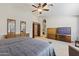 Open main bedroom featuring a ceiling fan, plush carpet, and seamless access to the en-suite bathroom with well-designed wooden cabinetry at 76 W Stacey Ln, Tempe, AZ 85284