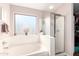 Bright bathroom featuring a soaking tub, a shower with glass doors, a window, and a rack of clothes at 8637 W Kathleen Rd, Peoria, AZ 85382