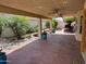 Spacious covered patio with ceiling fans, lush landscaping, and brick flooring for a relaxing outdoor living at 8804 E Sunnyside Dr, Scottsdale, AZ 85260
