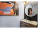 Powder room featuring a wood vanity, a modern faucet, and a stylish round mirror at 9818 W Pontiac Dr, Peoria, AZ 85382