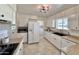 Bright kitchen features white cabinets, granite counters, tile floors, and stainless steel appliances at 10815 W Hatcher Rd, Sun City, AZ 85351