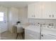 Laundry room features white cabinets, desk, and brick wall accents at 10815 W Hatcher Rd, Sun City, AZ 85351