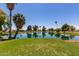 Scenic pond view with green lawn and trees under a bright blue sky at 10815 W Hatcher Rd, Sun City, AZ 85351