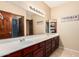 Bathroom featuring double sinks, large mirror, wooden cabinets and bright vanity lights at 11101 W Sieno Pl, Avondale, AZ 85392