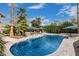 Resort-style pool with spa and waterfall feature is surrounded by palms, umbrellas, and a lush backyard setting at 11101 W Sieno Pl, Avondale, AZ 85392