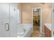Bright bathroom with a soaking tub and shower, tile flooring, and a doorway to a walk-in closet at 15430 W Sells Dr, Goodyear, AZ 85395