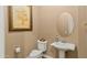 Charming powder room with pedestal sink, oval mirror, and decorative wall art at 15430 W Sells Dr, Goodyear, AZ 85395
