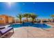 Inviting backyard pool features vibrant blue water, a small waterfall, lounge chairs, and swaying palm trees at 19084 N Toledo Ave, Maricopa, AZ 85138