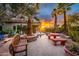 A well-designed backyard featuring an outdoor kitchen, pool, patio and lounge area with a fire pit, set against a sunset at 19644 N Majestic Vista Ct, Surprise, AZ 85387
