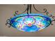 A close-up of an ornate chandelier with colorful glass and wrought iron detailing adds artistic flair to the room at 19644 N Majestic Vista Ct, Surprise, AZ 85387