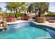 The blue tile pool with stone features includes a picnic table and lounge area, all surrounded by mature landscaping at 19644 N Majestic Vista Ct, Surprise, AZ 85387