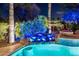 Backyard pool featuring a rock waterfall, lush landscaping, and decorative lighting for a tranquil ambiance at 19644 N Majestic Vista Ct, Surprise, AZ 85387