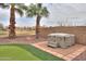 Relaxing backyard featuring a hot tub, putting green, and lush palm trees for a serene escape at 22139 N O Sullivan Dr, Maricopa, AZ 85138