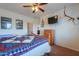 Well-lit bedroom featuring a wooden bed frame, mounted TV, and decorated with artwork and mounted antlers at 22139 N O Sullivan Dr, Maricopa, AZ 85138