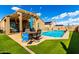 Attractive backyard featuring a pool, patio seating, pergola, and artificial grass at 23791 W Magnolia Dr, Buckeye, AZ 85326